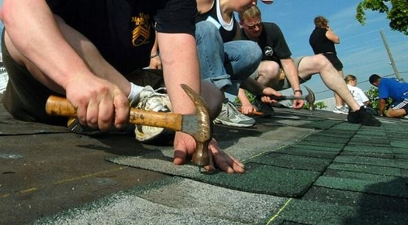 A roofing crew installs shingles on a house in Fort Lauderdale, Florida during a Habitat for Humanity project. U.S. Navy photo, public domain, via Wikimedia Commons