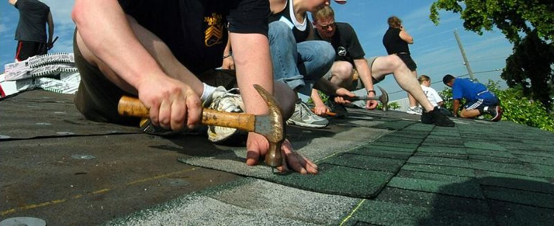 A roofing crew installs shingles on a house in Fort Lauderdale, Florida during a Habitat for Humanity project. U.S. Navy photo, public domain, via Wikimedia Commons