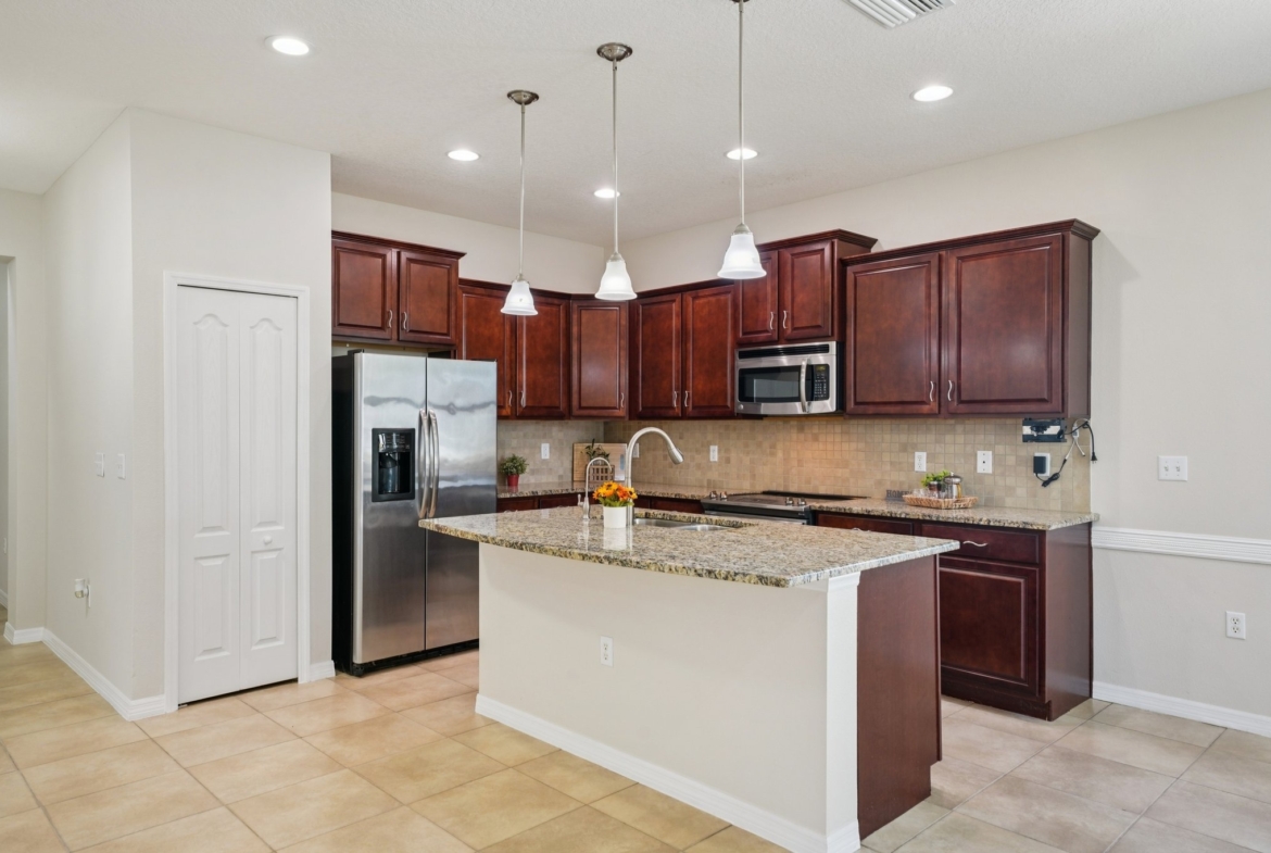 Kitchen with stainless refrigerator, granite island and breakfast bar in Summertree, New Port Richey FL