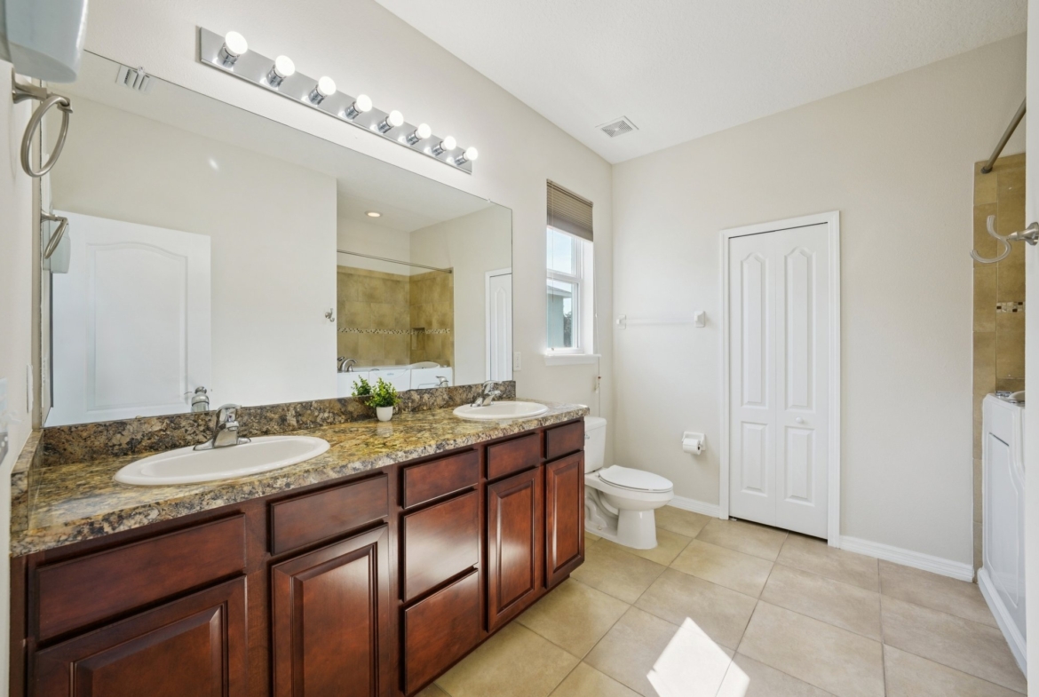 Primary bath with double sinks and granite counters at 11129 Kiskadee Cir, New Port Richey FL