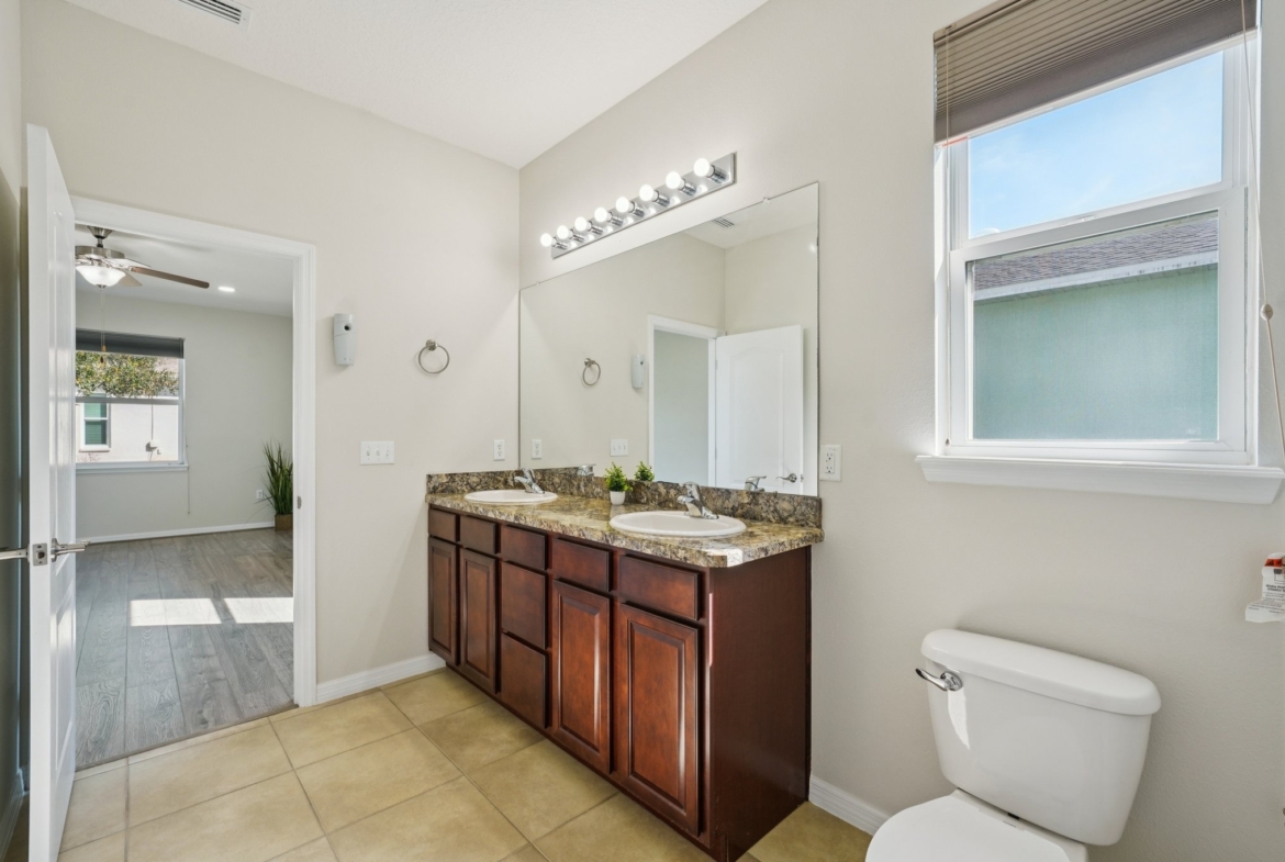 Primary bathroom vanity with granite counters and window in this Summertree 55+ home