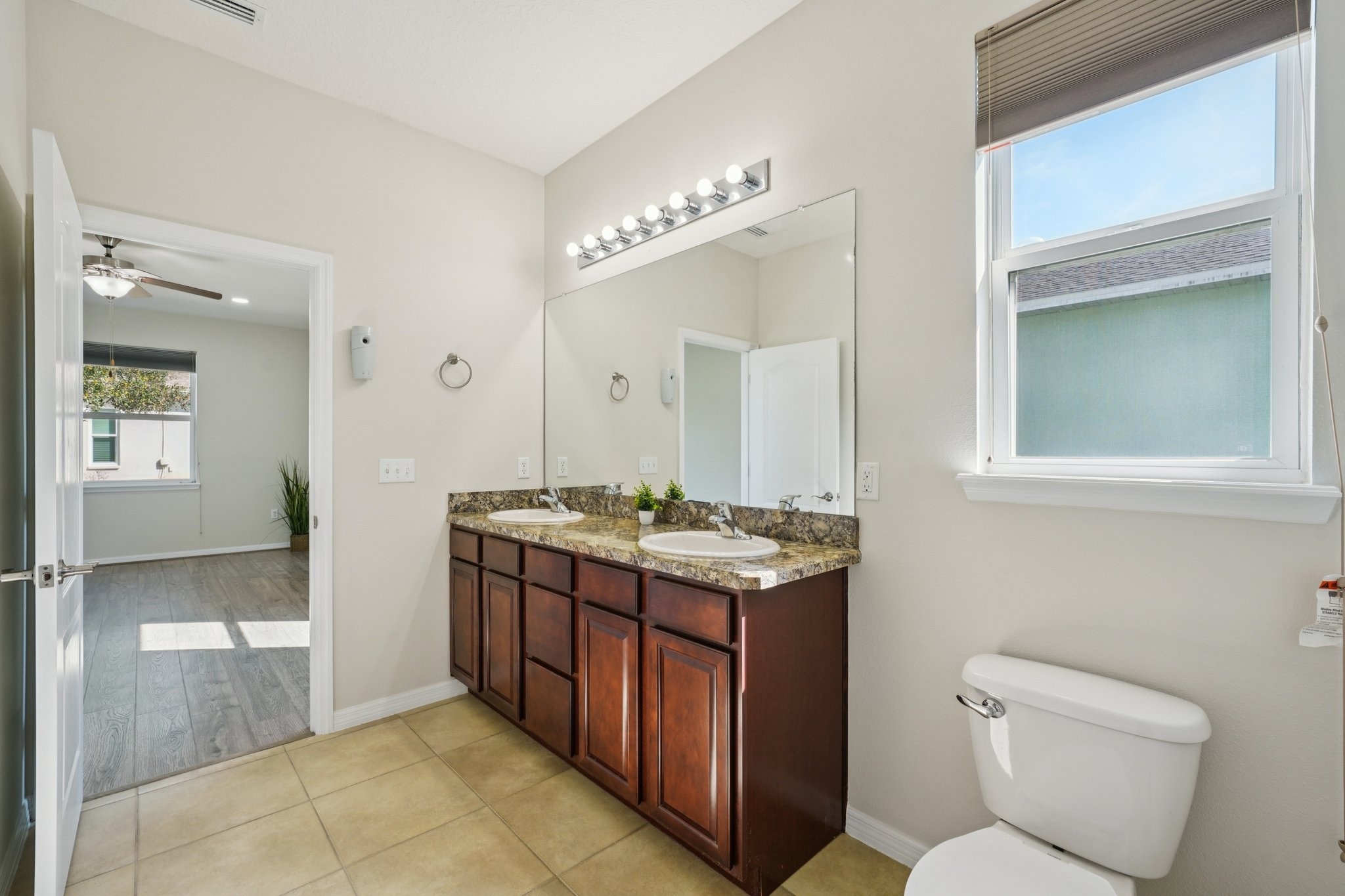 Primary bathroom vanity with granite counters and window in this Summertree 55+ home