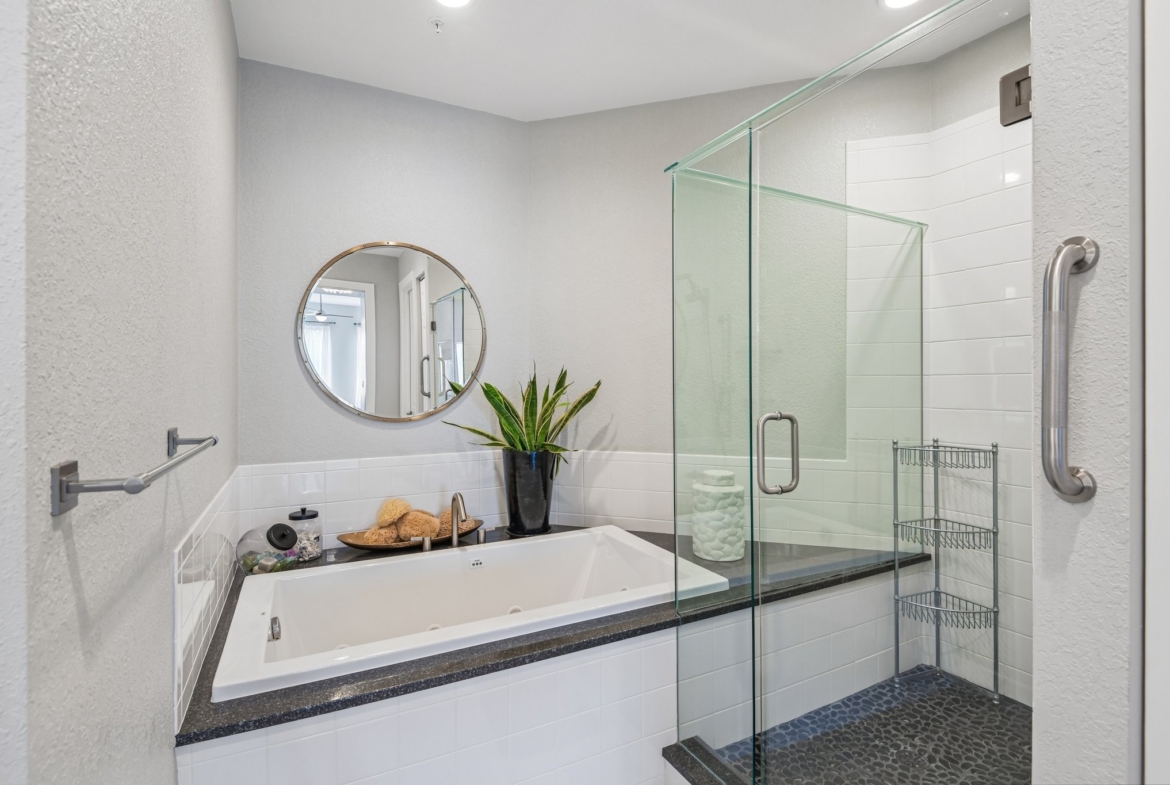 Primary bath with soaking tub and frameless glass shower at The Grande on Sand Key residence 101
