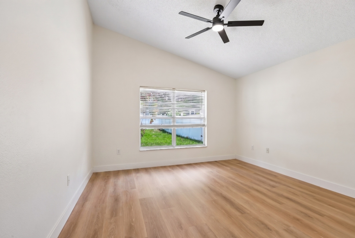 Bedroom with vaulted ceiling, ceiling fan and luxury vinyl plank flooring in Key Vista, Holiday FL