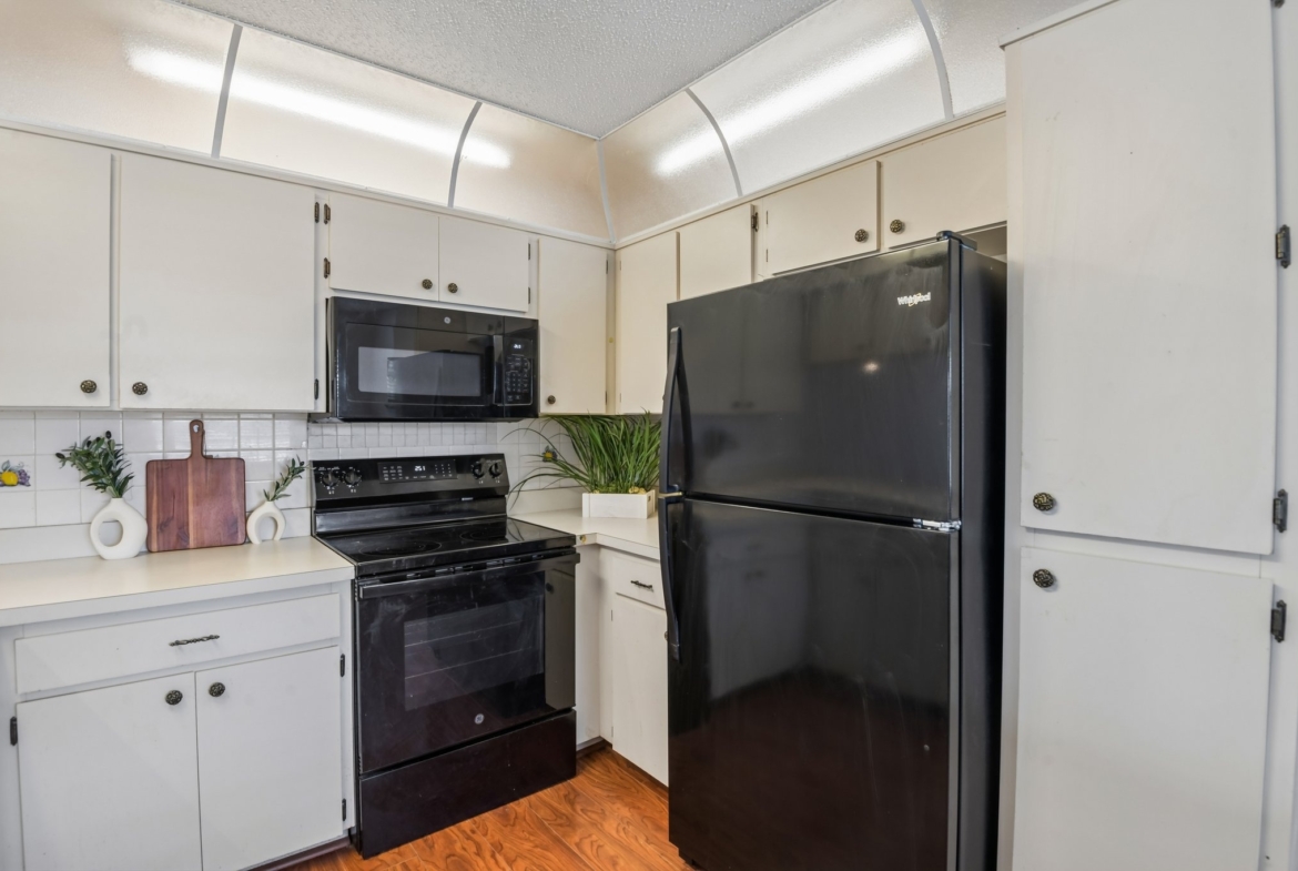 Kitchen with electric range and refrigerator in this newly painted Hudson FL 55+ condo