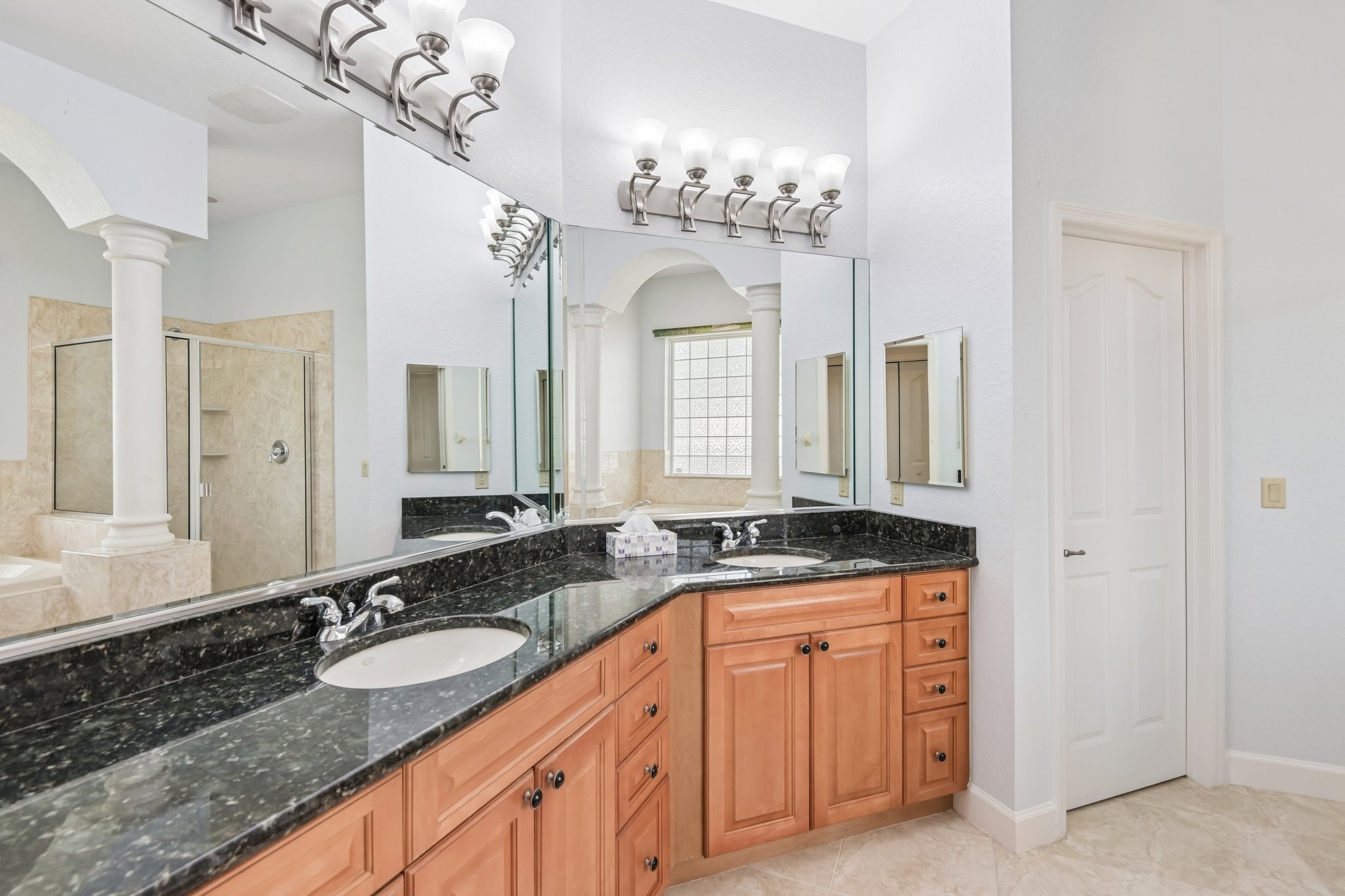 Primary bathroom with dual granite vanity and maple cabinetry at 8335 Cheyenne Dr, Seminole FL