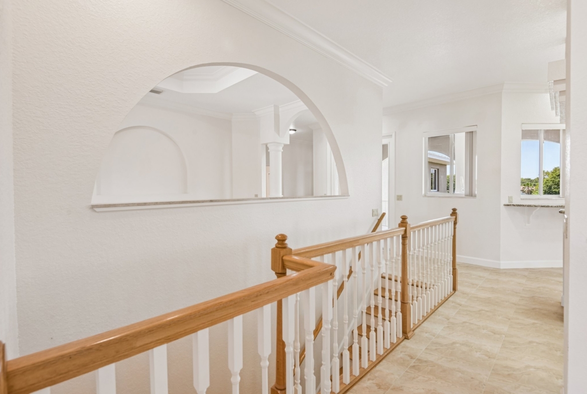 Wood staircase with arched window connecting the levels at 8335 Cheyenne Dr, Seminole FL