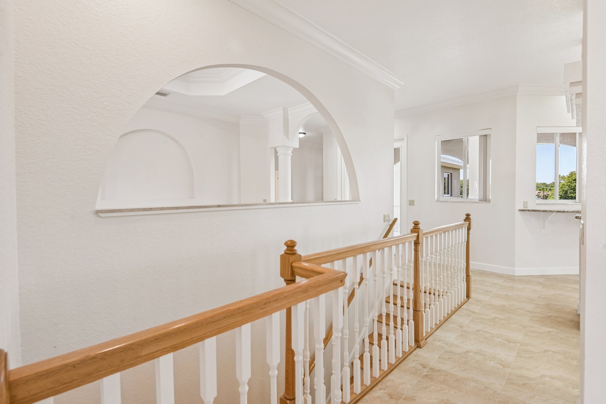 Wood staircase with arched window connecting the levels at 8335 Cheyenne Dr, Seminole FL