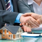 Real estate agent shaking hands with a homeowner over a house model and keys