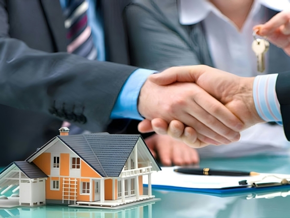 Real estate agent shaking hands with a homeowner over a house model and keys