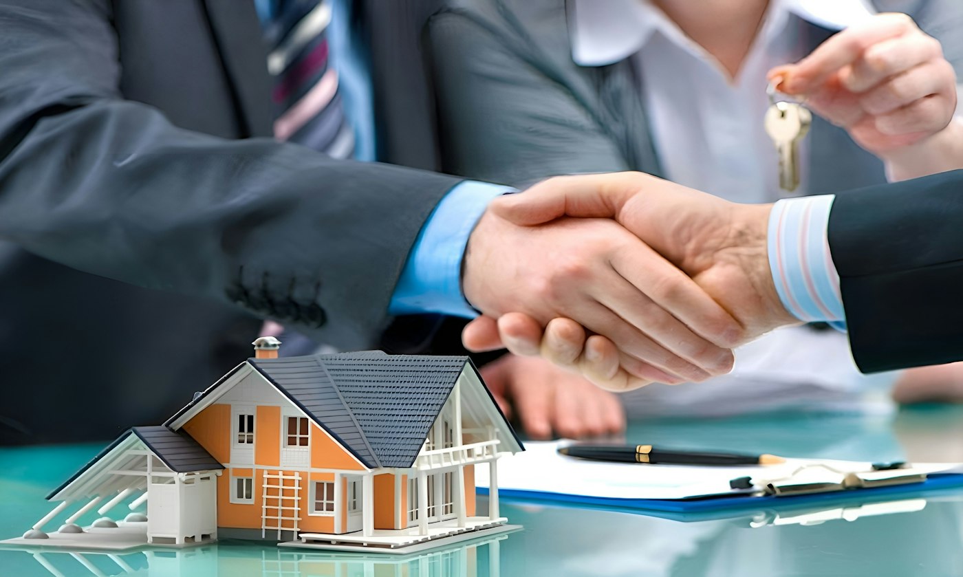 Real estate agent shaking hands with a homeowner over a house model and keys