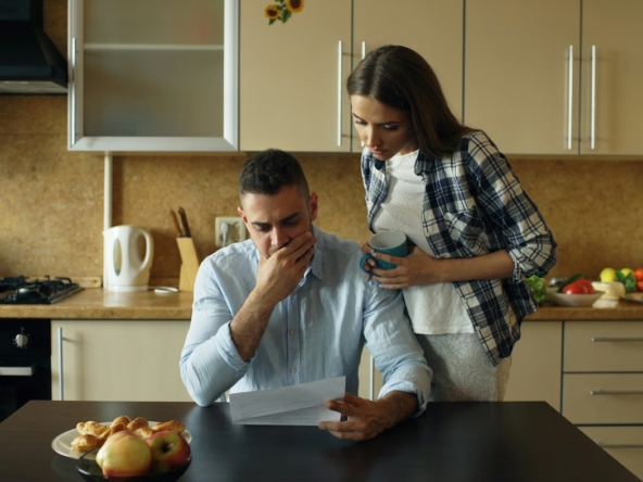 Couple reviewing mortgage bills at the kitchen table, considering a short sale