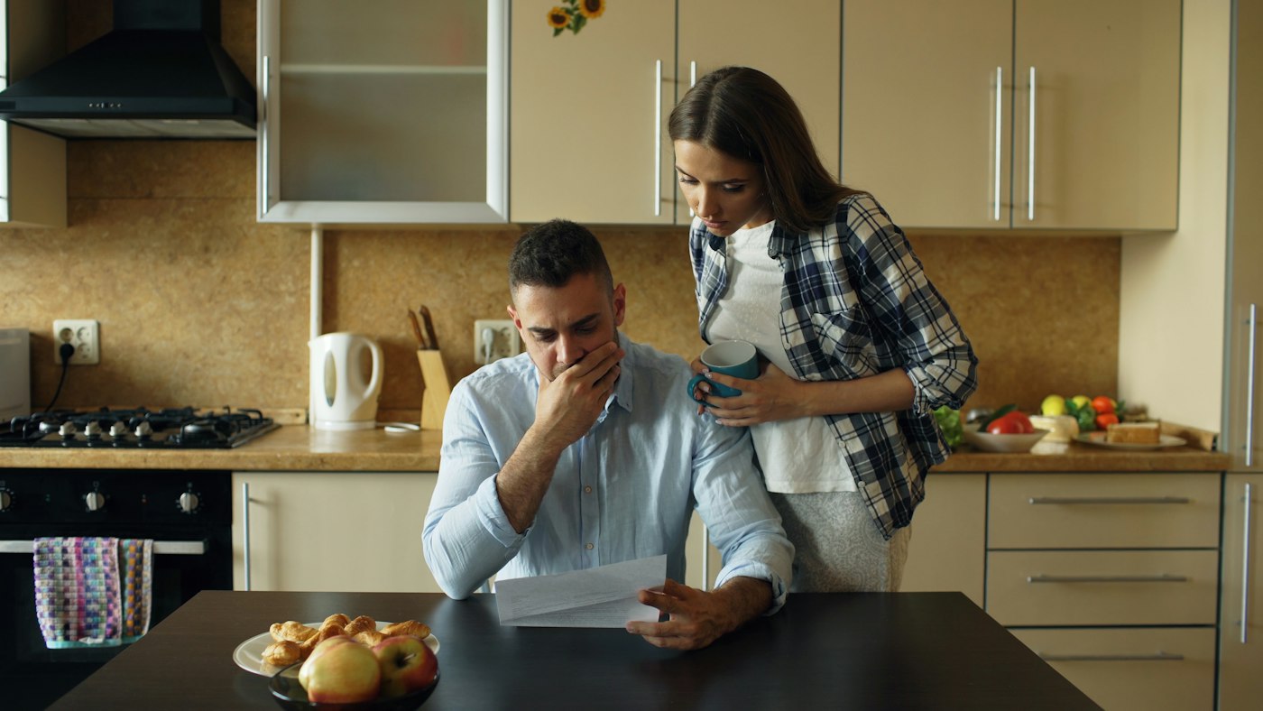 Couple reviewing mortgage bills at the kitchen table, considering a short sale