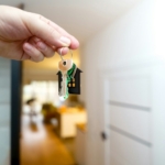 Hand holding house keys at the front door after closing