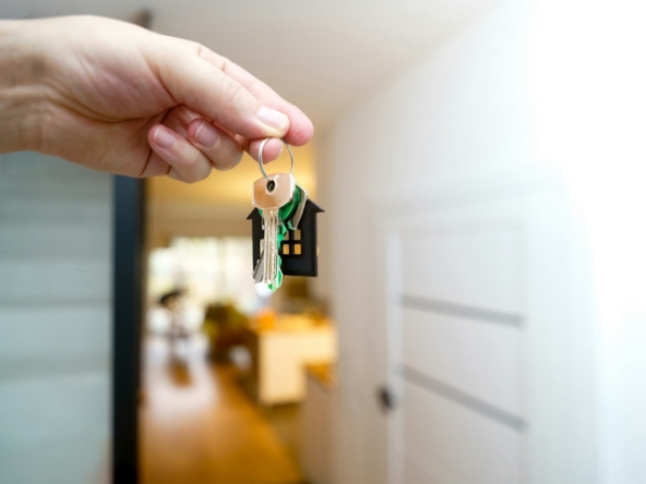 Hand holding house keys at the front door after closing