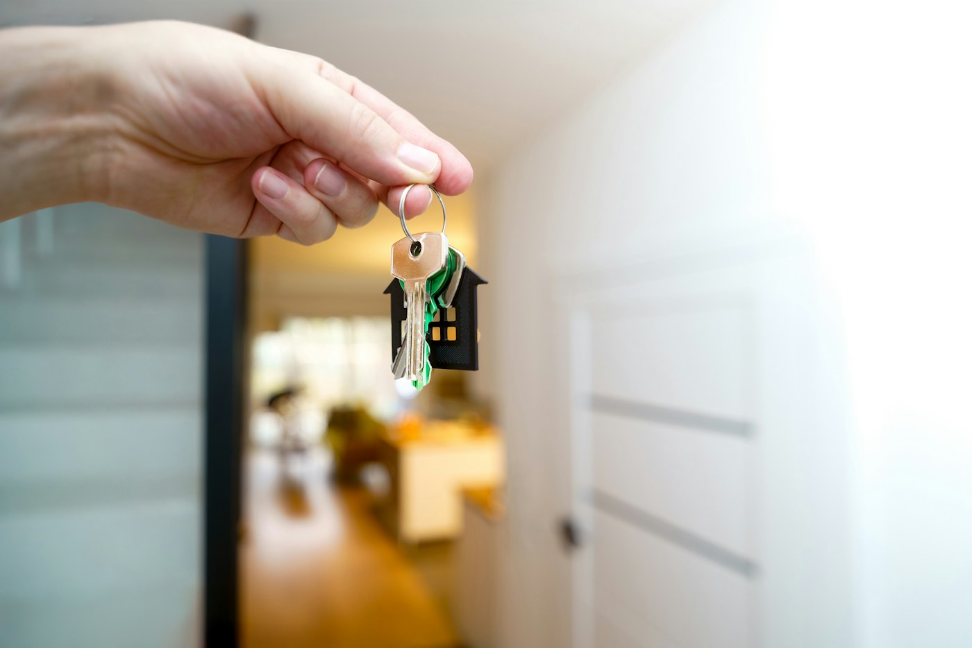 Hand holding house keys at the front door after closing